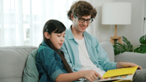 daughter and dad sitting on couch reading during family therapy program.